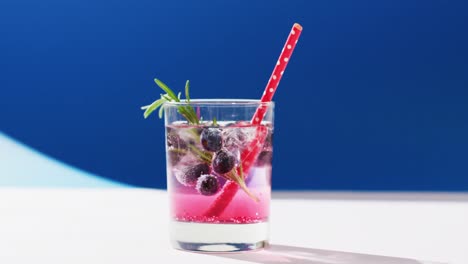 Close-up-of-transparent-drink-with-bluberries-on-blue-background