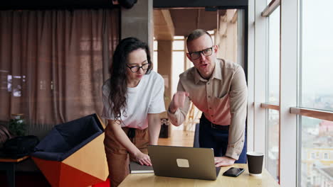 solving problems at work. male and female colleagues bent over the laptop, talk searching the solution.