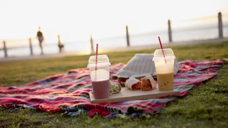 primer plano de una manta con batidos y tortillas en un picnic en el paseo marítimo, cámara lenta