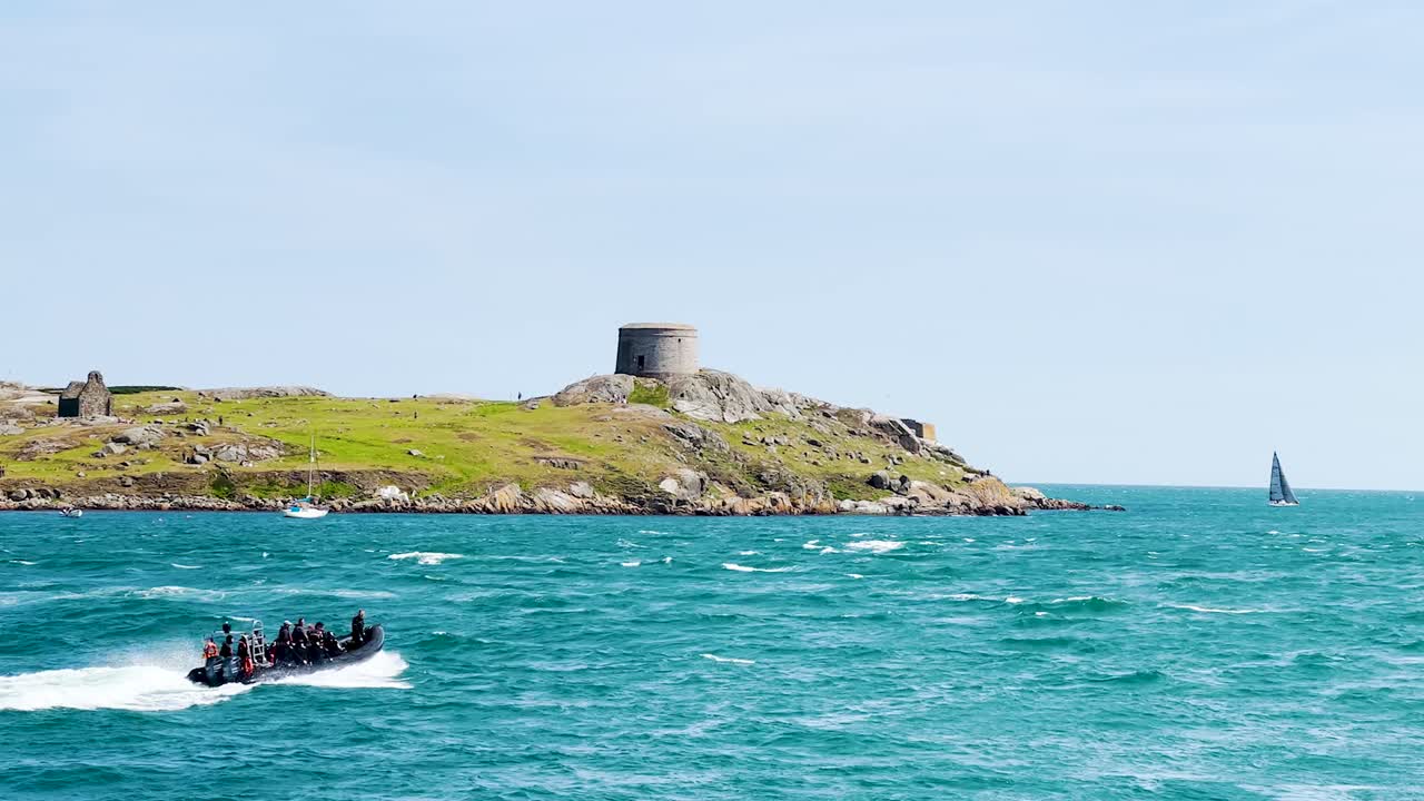Group of scuba divers in a speedboat traveling to the dive site while passing The Dalkey Island on a sunny day