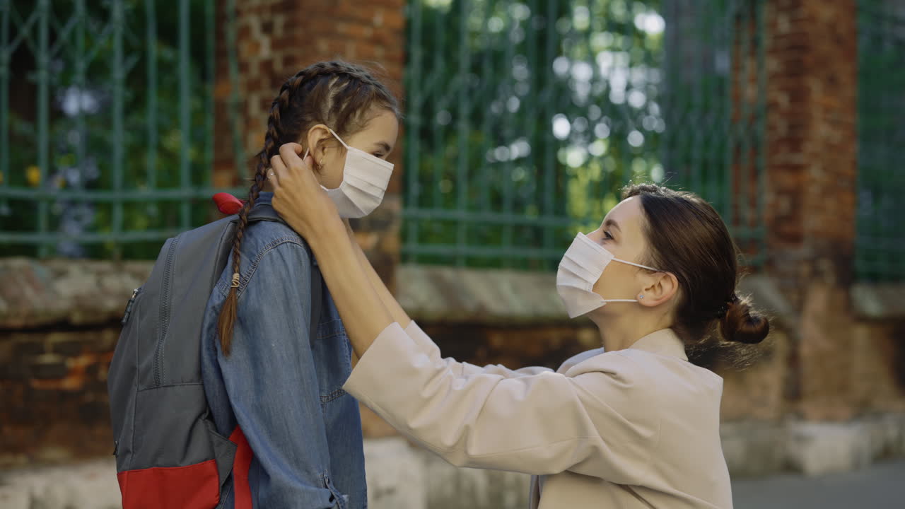 Mother helping daughter put on mask before school