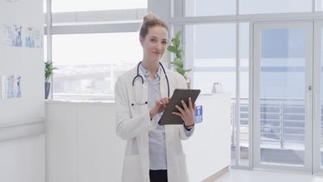 Portrait-of-happy-female-doctor-using-tablet-and-smiling-in-hospital,-in-slow-motion