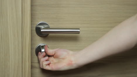 close up of caucasian right hand closes wooden door and locks chrome deadbolt