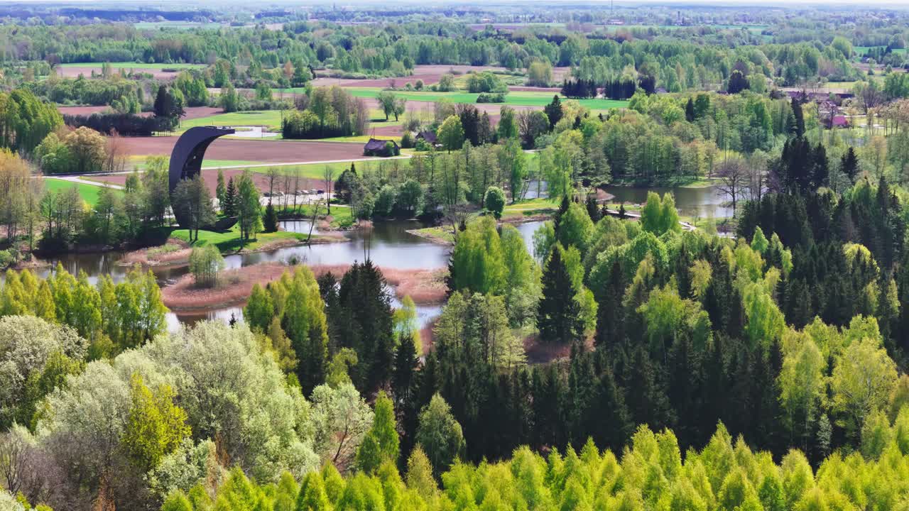 A Magnificent View Shows the Kirkilai Observation Tower Overlooking the Karst Lake and Dense Flora in Biržai Regional Park, Lithuania - Orbit Drone Shot