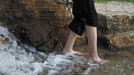 barefoot person walking in a waterfall