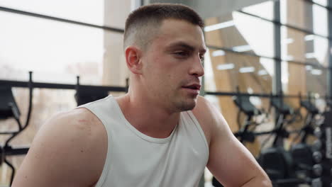fitness fanatic takes recovery break after intense elliptical workout breathing deeply allowing muscles to recover in modern gym environment sweat glistening on skin as he pauses to rest and hydrate