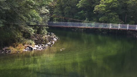 Toma-Panorámica-Del-Río-Tropical-Y-El-Puente-De-Cadena-De-Madera-Que-Conecta-La-Selva-Y-La-Selva-Tropical