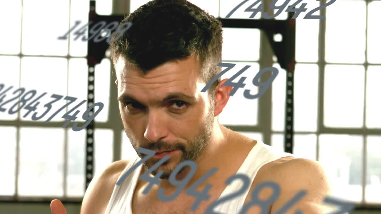 Male athlete raising guard and punching toward camera in gym, floating numbers tracking power