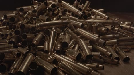 extreme close zoom out of large pile of bullet cases on a wooden surface