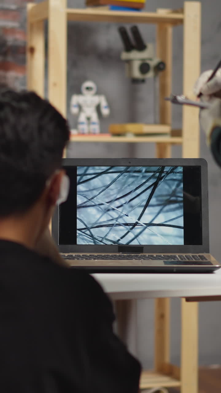 Blonde little girl scans elder brother hair with probe to learn texture via laptop and black assistant writes notes at fun lesson in laboratory