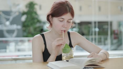 girl reading book and drinking beverage in cafe