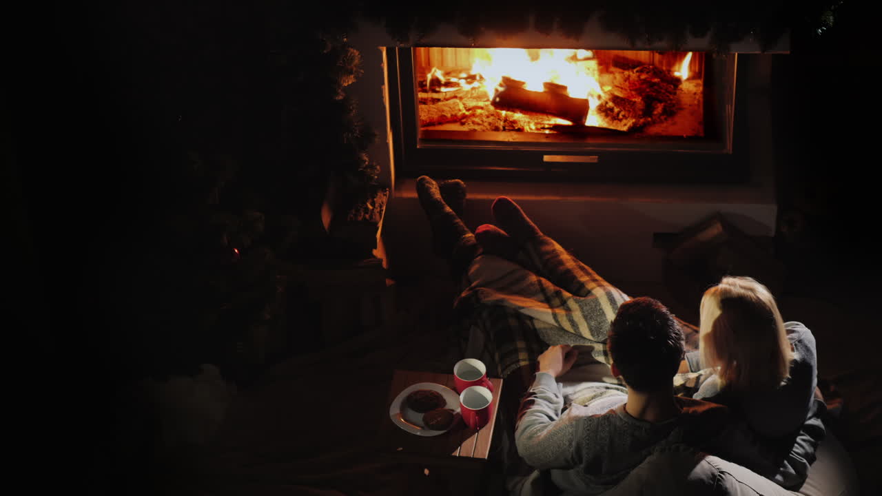 pareja joven relajándose en casa junto a la chimenea concepto de hogar cálido y confortable