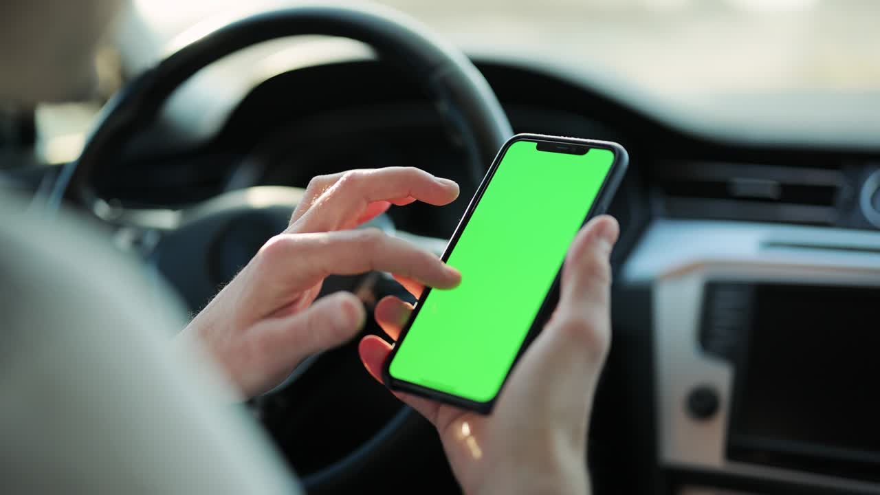 cerca de la mano del hombre sosteniendo un teléfono móvil con una pantalla de maqueta verde vertical en el coche. tecnología de teléfono inteligente clave de croma teléfono celular pantalla de mensaje táctil mano