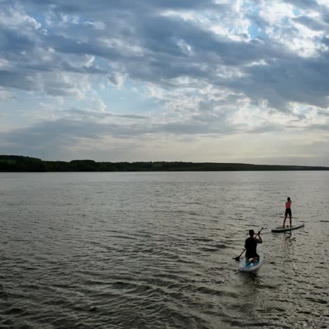 sporty couple during vacation. couple standing firmly on inflatable sup board and paddling