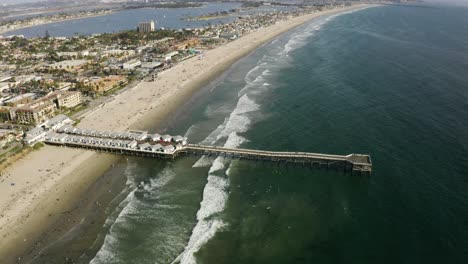 aerial shot tilting down to a pier at pacific beach, san diego