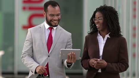 Smiling-lawyers-looking-at-tablet-during-stroll