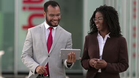 smiling lawyers looking at tablet during stroll