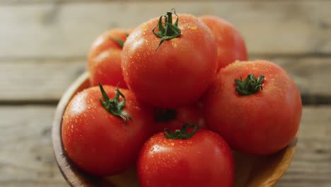 vídeo de primer plano de tomates frescos en un cuenco sobre fondo de madera