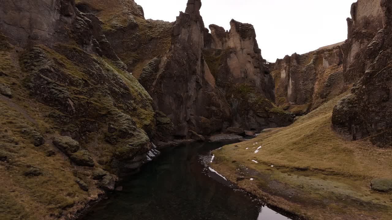 En smal flod flyter mellan branta mossbeklädda klippor i Fjaðrárgljúfur kanjon nära Kirkjubæjarklaustur på Island.