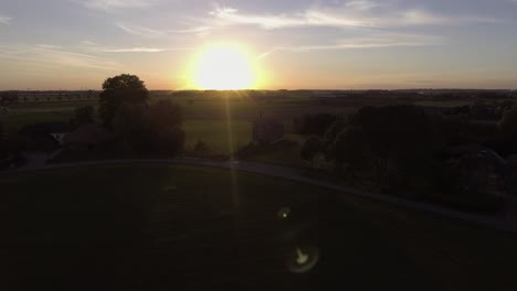 a drone shot flying to the left, with the sun going down behind a church