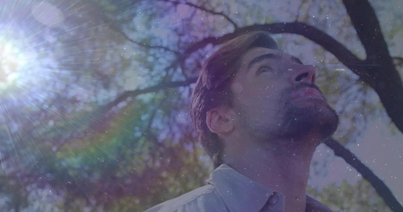 Destello solar atrayendo la mirada, hombre inclinándose hacia arriba buscando bienestar, la cámara inclinándose, una superposición de arcoíris cruzando el rostro.