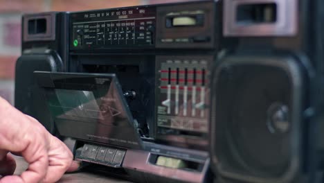 hand inserts the cassette into the old cassette player and plays it by pressing the play button.