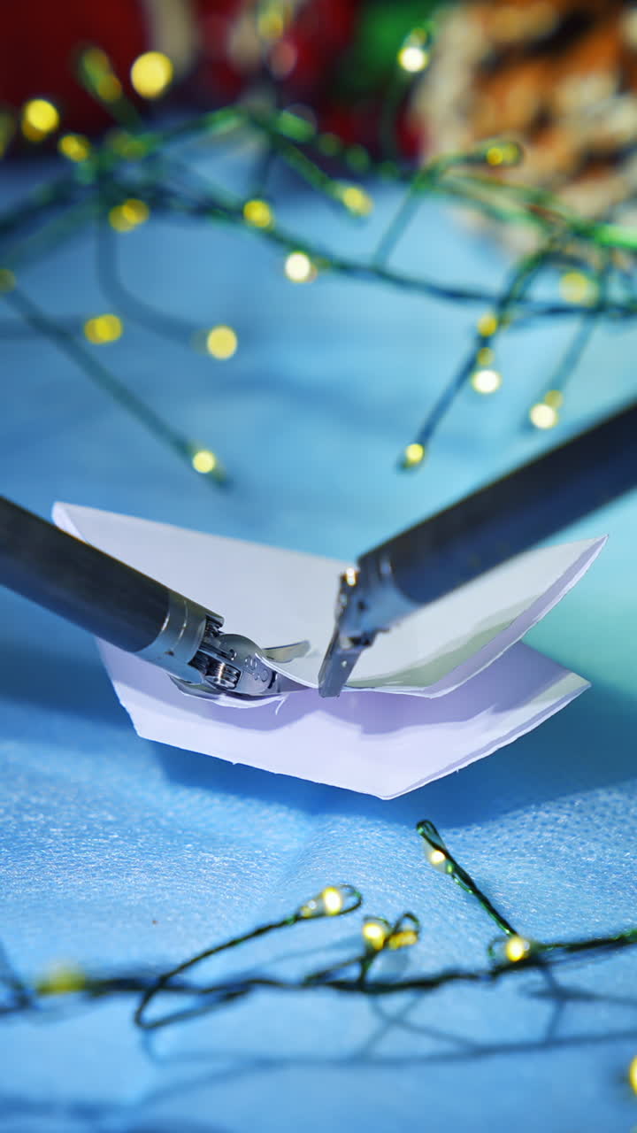 Artificial intelligence robot preparing snowflake from paper while preparing to the Christmas. Cropped view. Vertical video