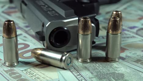 pistola y balas en billetes de cien dólares