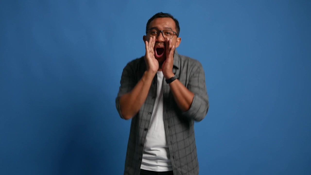 Happy Asian adult man looking at camera and shouting with excitement in celebrating moment