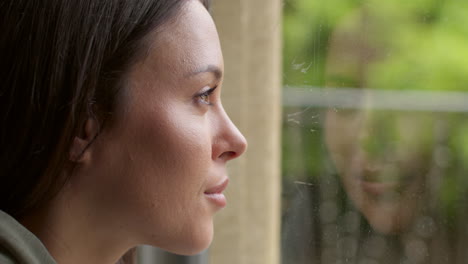 close up of woman at home in lounge looking out of window