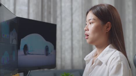 Close Up Side View Of Asian Female Automotive Designer Yawning While Working On 3D Model Of Ev Car On The Desktop Computers In The Studio