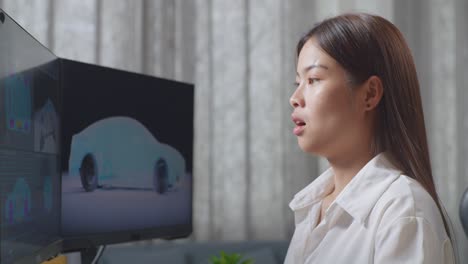 close up side view of asian female automotive designer yawning while working on 3d model of ev car on the desktop computers in the studio