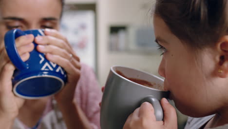 mother and daughter drinking hot chocolate together in kitchen happy mom caring for little girl enjoying homemade delicious beverage at home