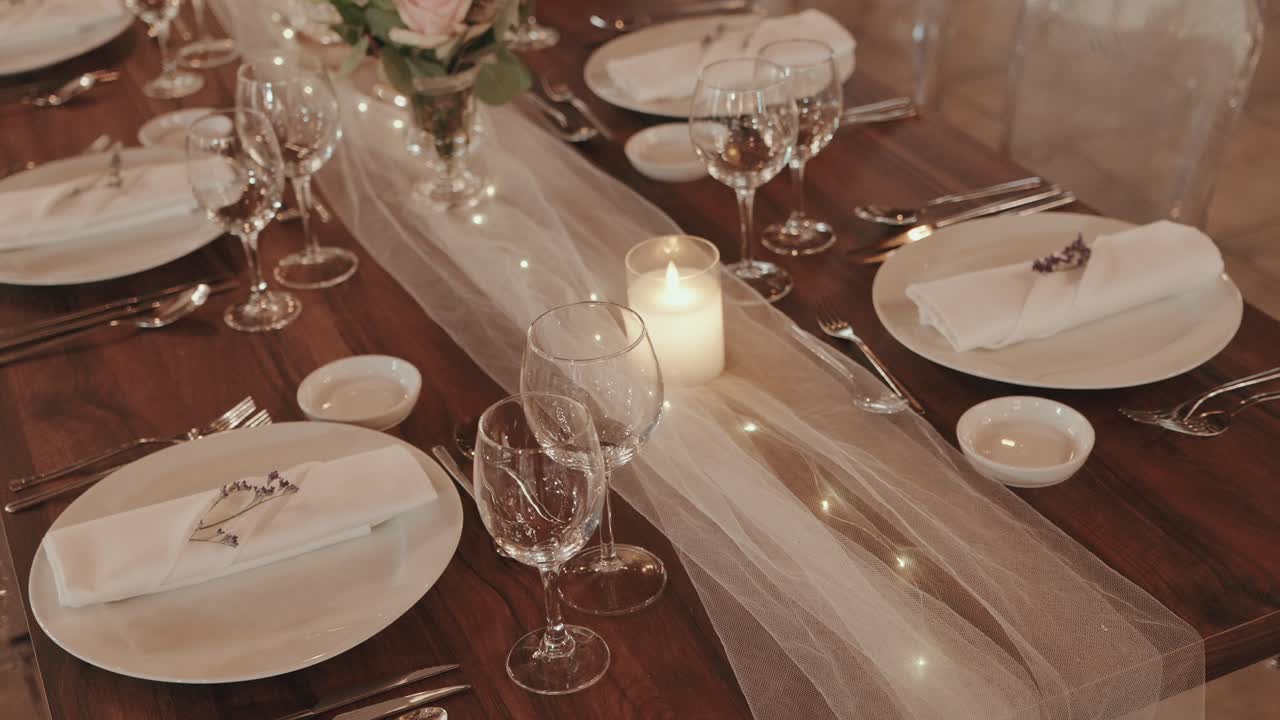 Decorated wedding dinner table with candle, flowers, and glassware