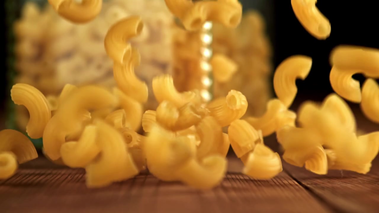 Maccheroni secchi che cadono su un tavolo di legno al rallentatore