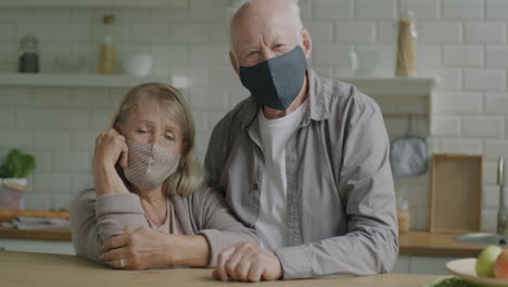 elderly couple wearing masks in kitchen