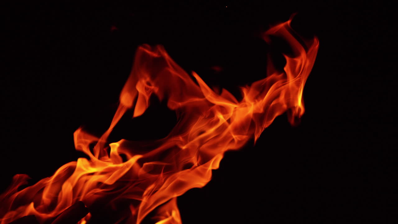 Flame of campfire leaning to the right. Wood burning in the darkness close up.