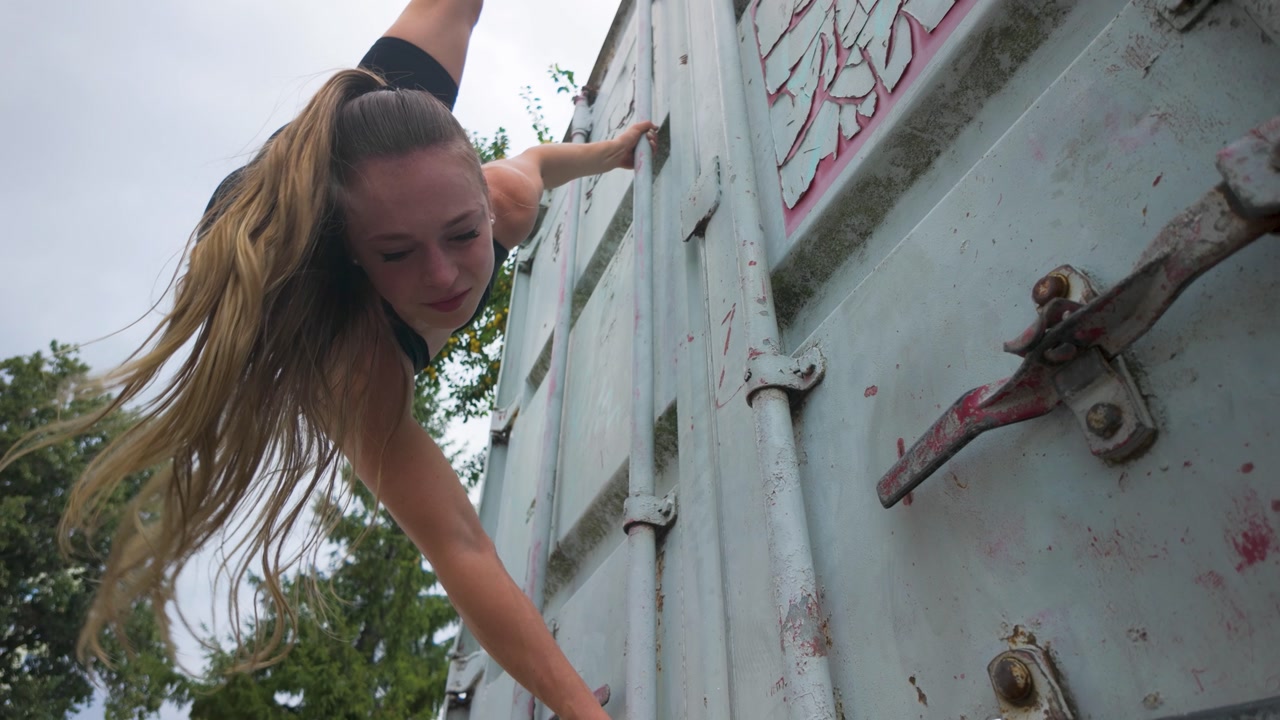 Strong woman performing street parkour over a street container.