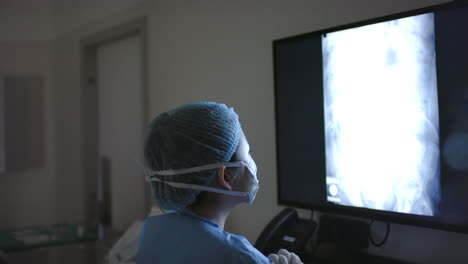 asian female surgeon looking at x-ray scans in operating theatre, slow motion