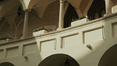 soft sunlight casts shadows on an elegant arched balcony with flowers and stone columns
