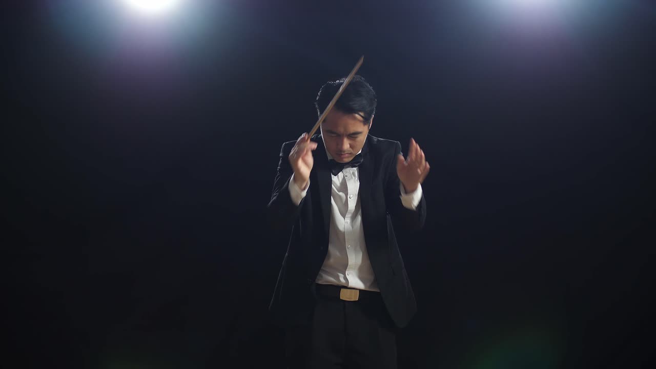 conductor asiático hombre sosteniendo un bastón cerrando los ojos y mostrando el gesto en el estudio negro