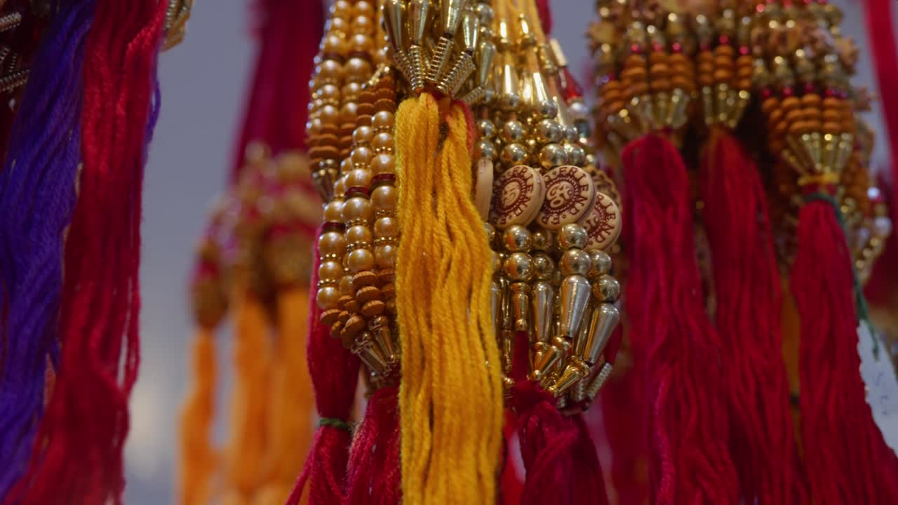 different types of beautiful rakhis with beads, colorful threads are hanging in bunches and flickering celling lights in the background, during Raksha Bandhan Festival season in India,4k, parallax