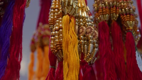 different types of beautiful rakhis with beads, colorful threads are hanging in bunches and flickering celling lights in the background, during raksha bandhan festival season in india,4k, parallax