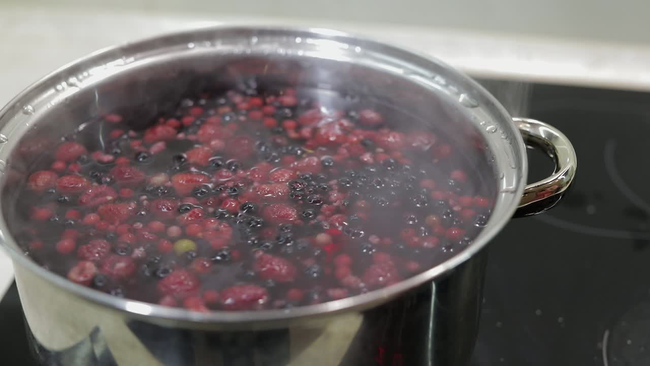 Stir the berries in pot with boiling water. Cooking compote. Kitchen
