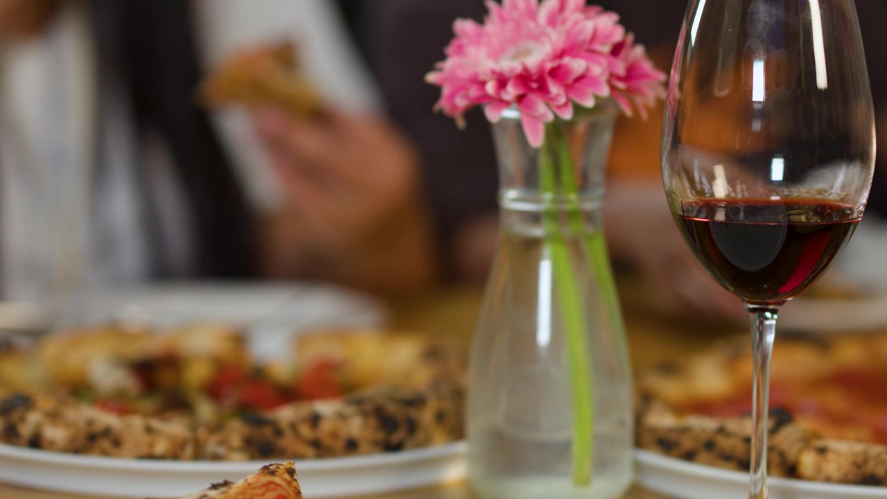 Amici che gustano pizza e vino rosso a un tavolo di ristorante