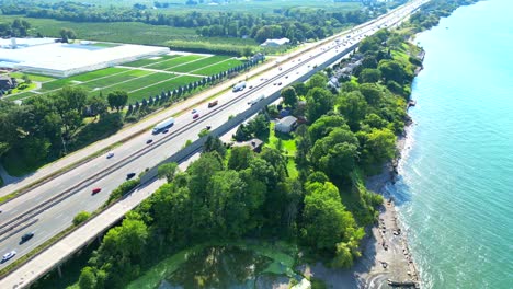 Viel-Befahrener-Qew-highway-Zwischen-Creekside-gewächshäusern-Und-Seeuferstränden.-Luftaufnahme