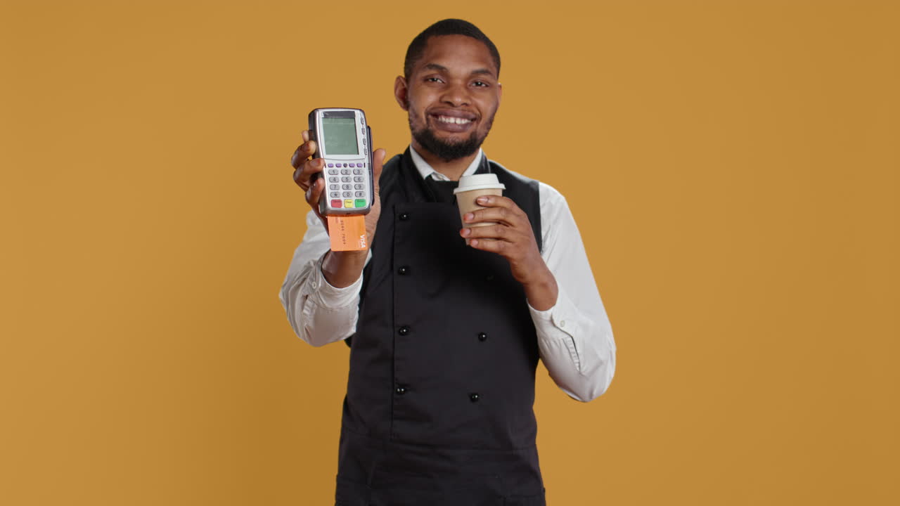 camarero profesional y amigable mostrando la terminal pos con una tarjeta de crédito