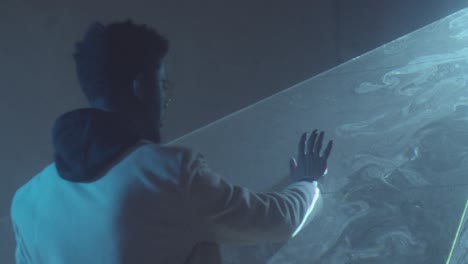 hombre negro pasando por una hoja plana de luz láser en una habitación oscura