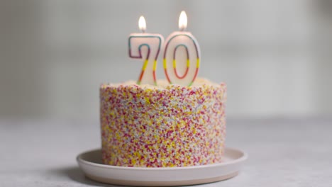 장식으로 덮인 스튜디오 샷 생일 케이크와 칠십 번째 생일을 축하하는 촛불이 날아가고 있다