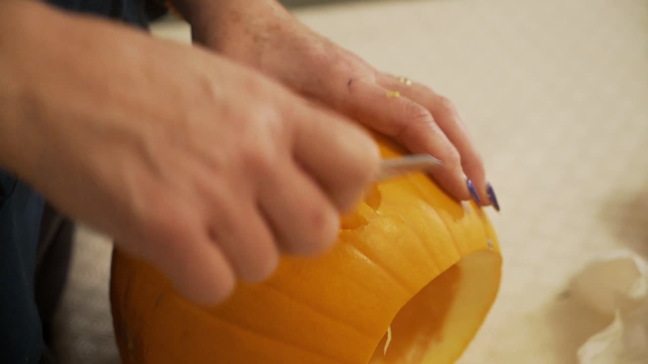 Close up of a lady carving eyes into a pumpkin for Halloween